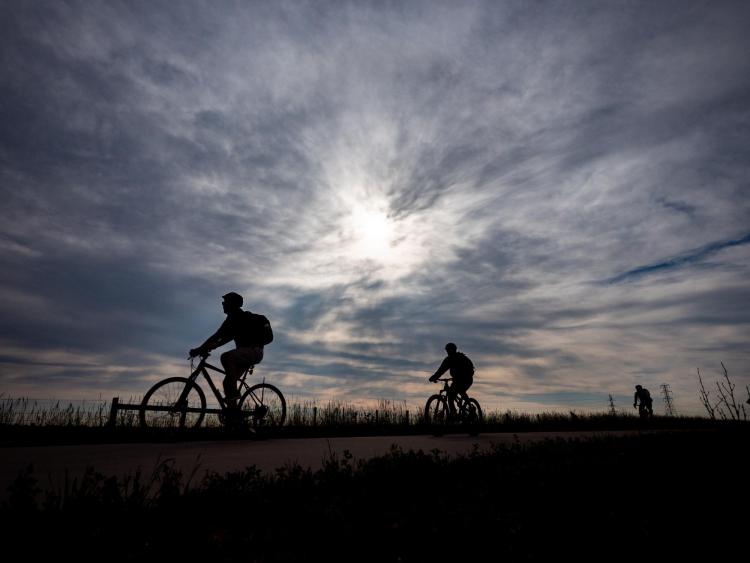 Silhouette of two people biking to work