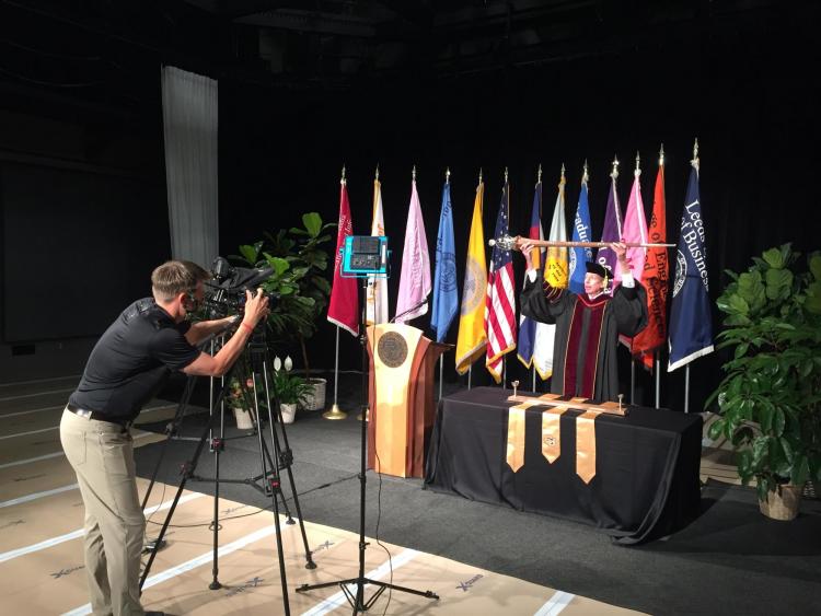 A camera records Bud Coleman as he lowers the ceremonial mace