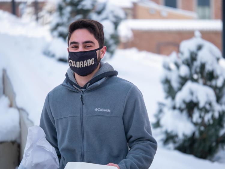 student outside on campus wearing CU mask