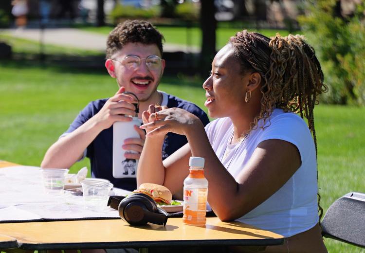 two campus community member sit at an outdoor table together