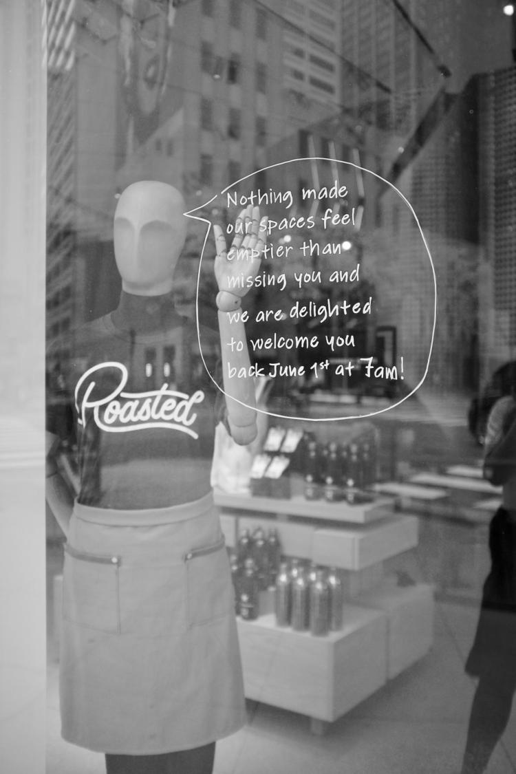 Mannequin and handwritten note in retail display window that reads: 'Nothing made our spaces feel emptier than missing you, and we are delighted to welcome you back June 1st at 7 am!'
