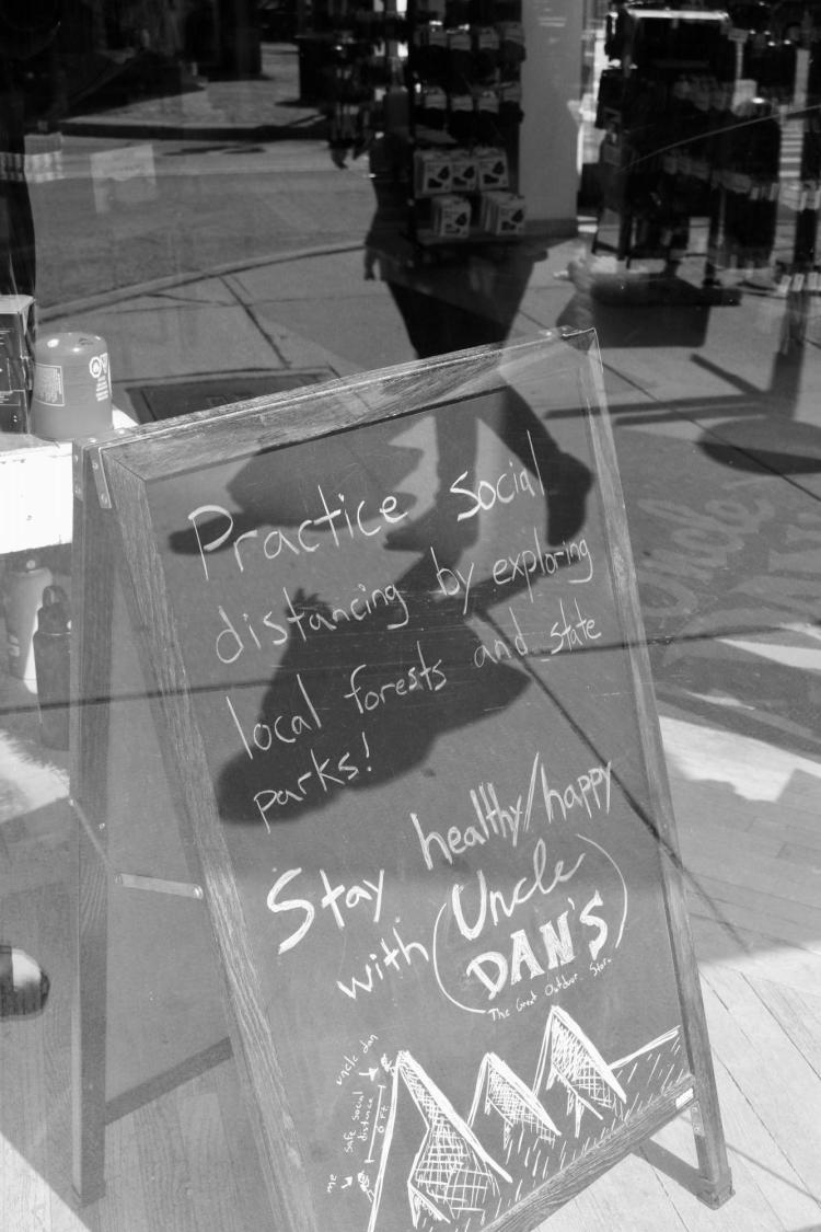 Local business sidewalk sign reads: 'Practice social distancing by exploring local forests and state parks!'