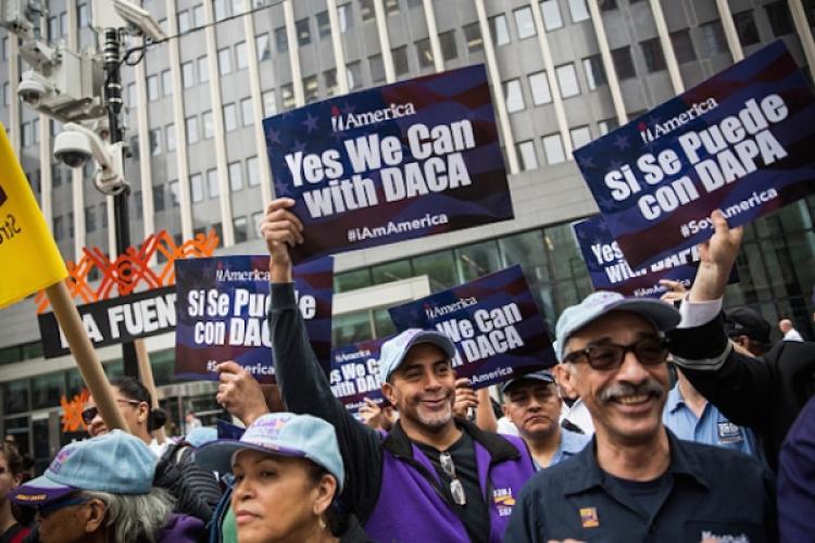 Activists hold up signs that say "Yes We Can with DACA" in English and Spanish