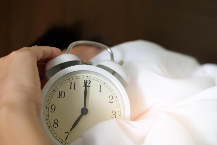 person in bed turns off an alarm clock