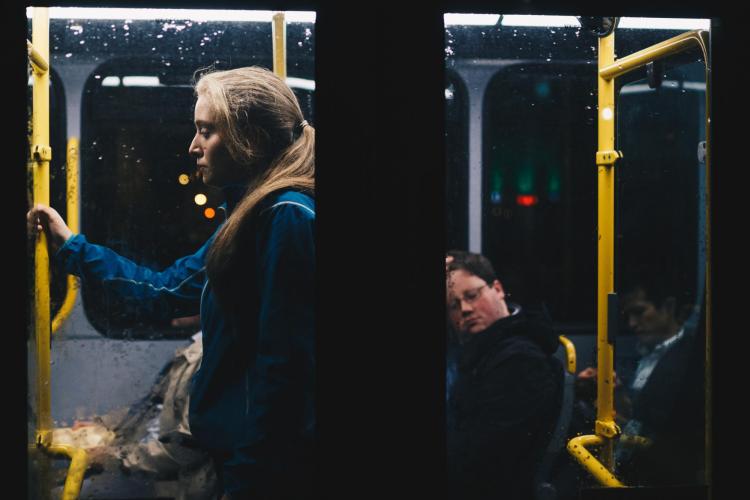 Woman stands during a dark bus ride