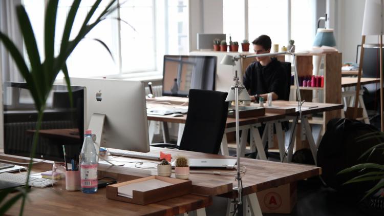 Person sits at desk in open-floor office