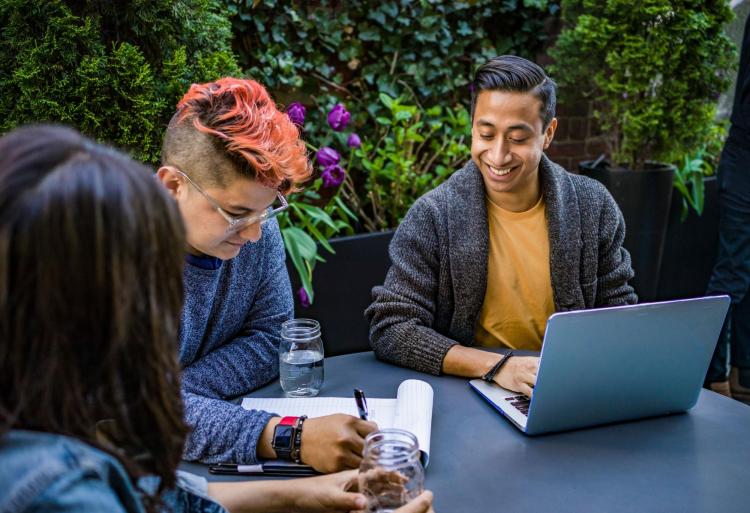 Young adults sitting at a table with a laptop
