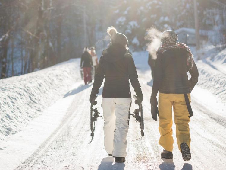 Group of friends walking with snowshoes in hand