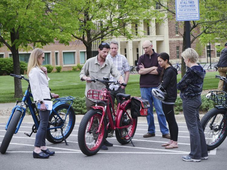 Campus community members gather around electric bikes during the 2018 Alternative Fuel Vehicle Ride-n-Drive event