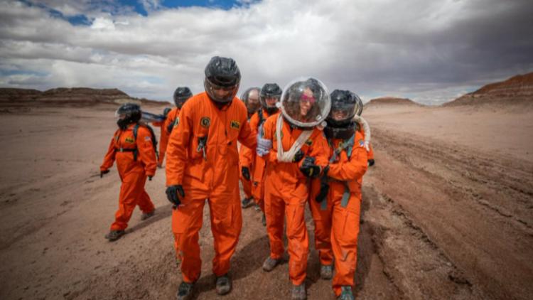 Group of students in astronaut gear walk in a simulated Martian environment