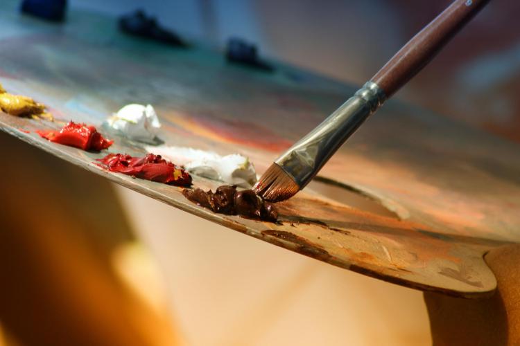 Artist dips brush in paint