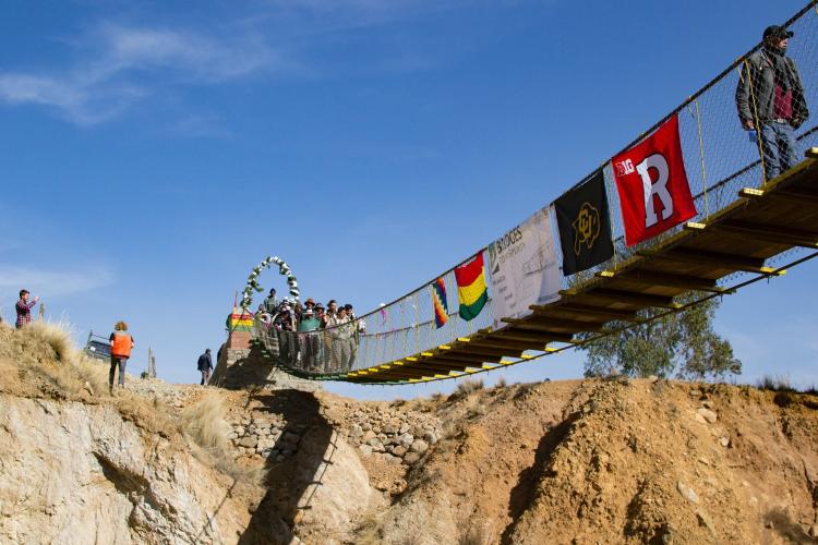 A suspension bridge with a CU Boulder flag