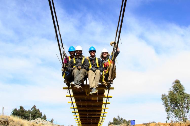CU Boulder engineering students sit on suspension bridge