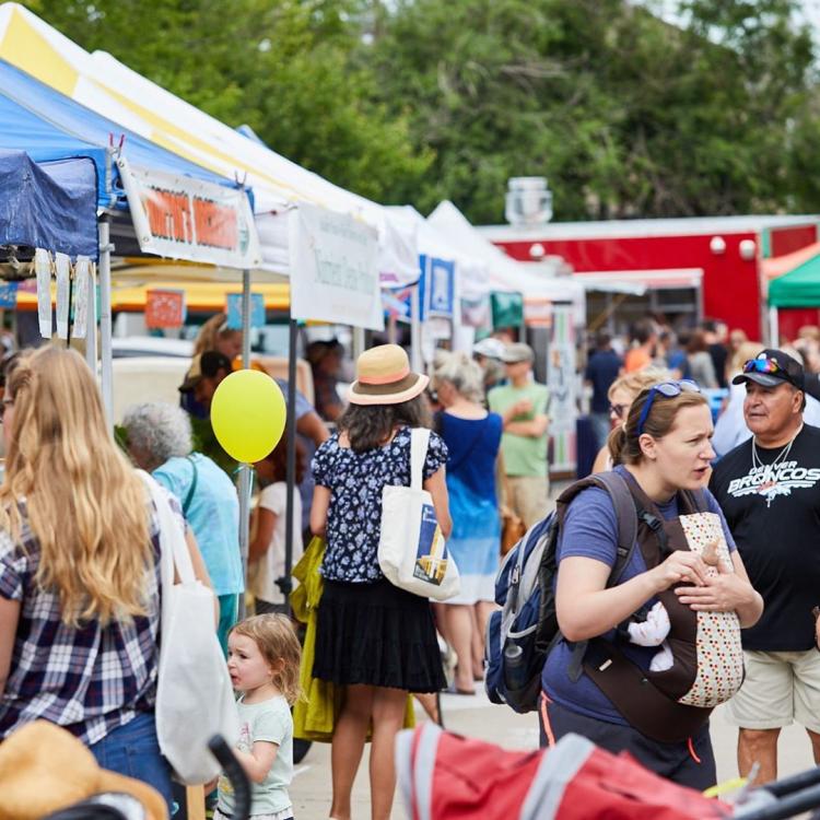 people walk through farmers market stands
