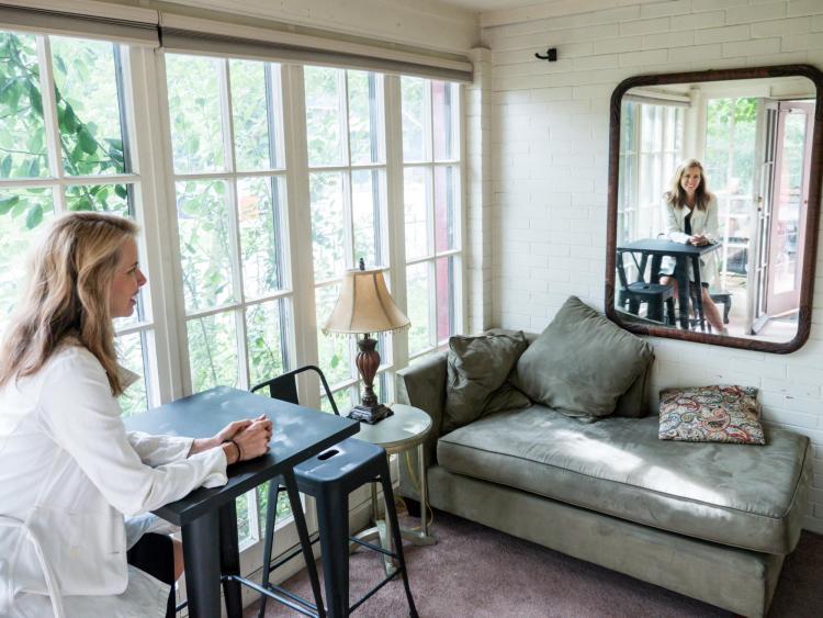 Beth Osnes looks across the room into a mirror