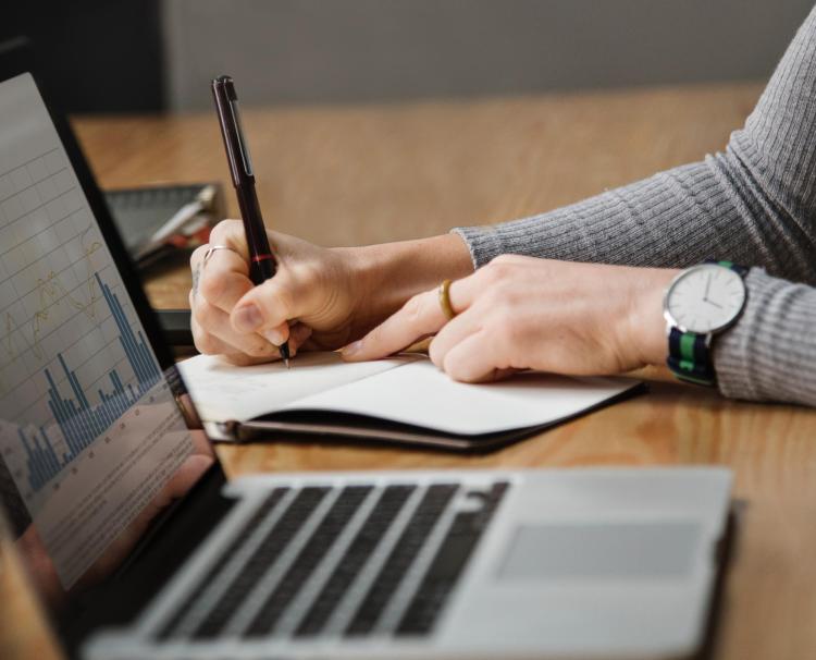 Person works on a budget with notepad and laptop
