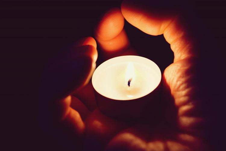 Person holds votive candle in hand