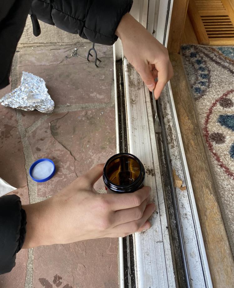 Hands scraping in door frame with screwdriver