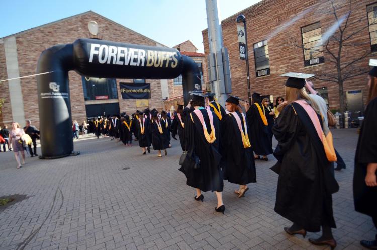 Graduates walk under ForeverBuffs arch during commencement
