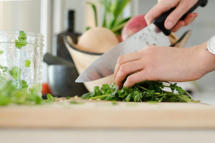 Person cutting up cilantro in kitchen