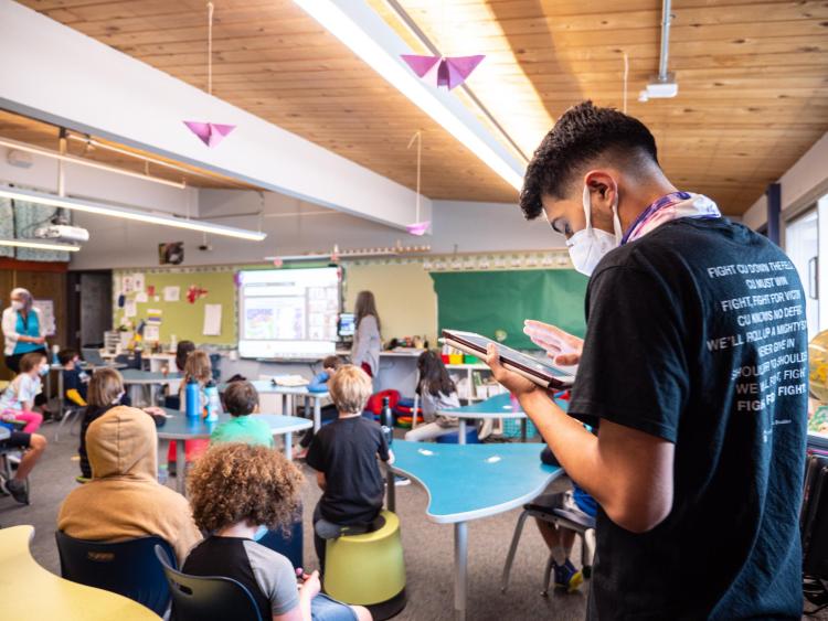 Ricardo Reyes takes air quality measurements from the back of a classroom filled with kids