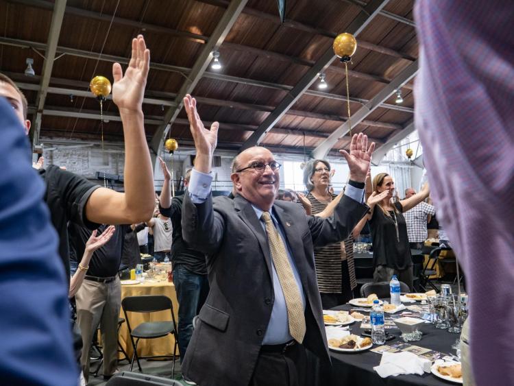Chancellor DiStefano raises hands at football kickoff luncheon