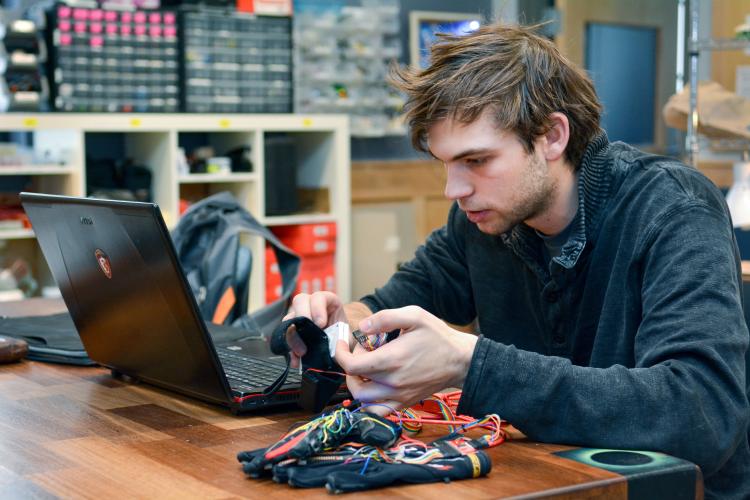 Technology, Arts and Media student Kristof Klipfel works at a computer with his "piano gloves"
