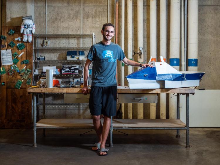 Earl Potters, a sophomore in computer science at the CU Boulder College of Engineeering and Applied Science, standing by his roboboat in a lab.