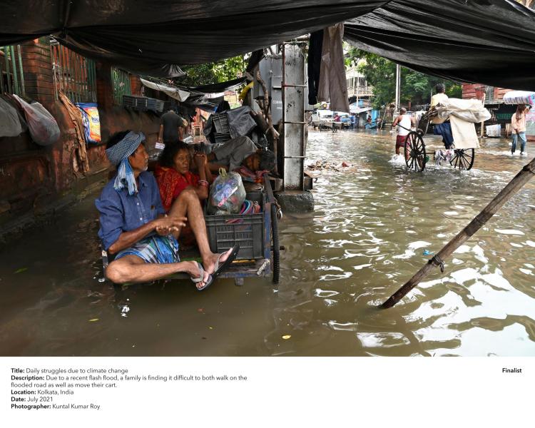 Due to a recent flash flood, a family is finding it difficult to both walk on the flooded roads as well as move their cart.