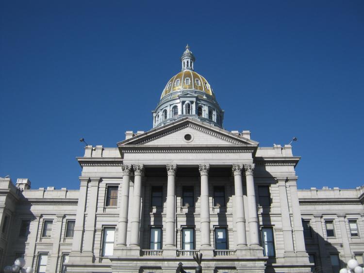 The tower of the state capitol building in Denver, Colorado, appears against a clear blue sky.