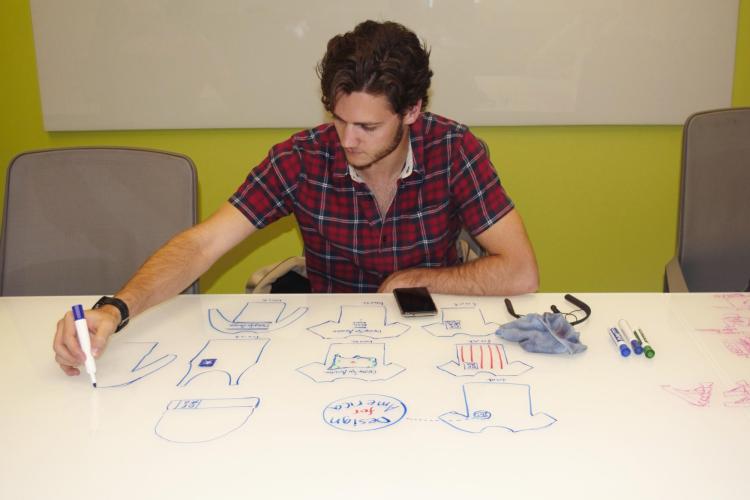 Design for America student sketches ideas on dry erase board