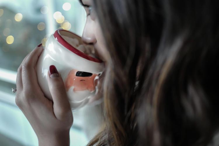 Person drinking hot chocolate out of a Santa mug