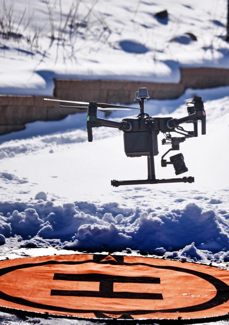 A drone, used to create a detailed map of the Marshall Fire destruction, hovering over a snowy ground