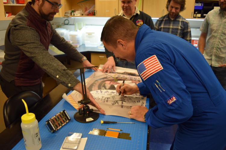 Fischer autographs a poster during visit. Photo from CU Engineering.