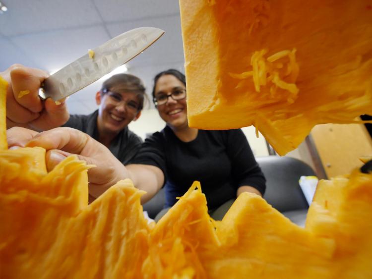 Chantal Lehl, right, and Vanessa Luna carve out their entry in the engineering college's pumpkin carving contest. Photo by Glenn Asakawa.