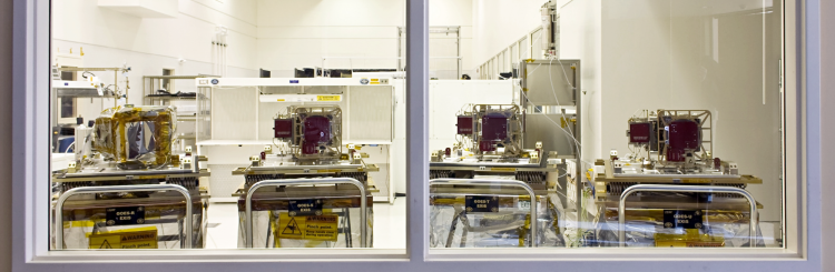 Four machines sit on carts on the other side of a glass window
