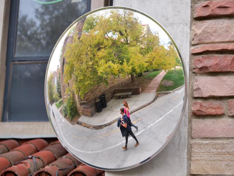 students walking on campus as seen reflected in a mirror