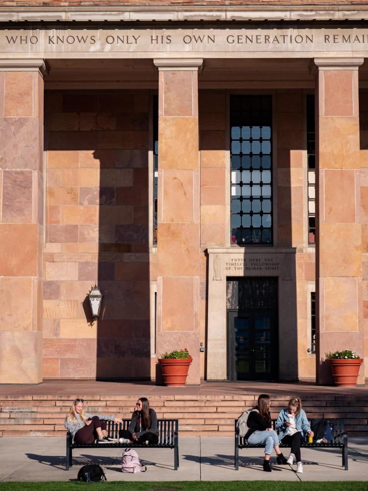 Students sitting on benches outside of Norlin Library