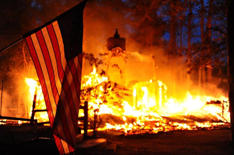 Wildfire destroys home, American flag in foreground