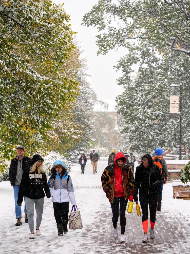 Students make their way to class during the first snowfall of the year on Oct. 10, 2019. (Photo by Patrick Campbell/University of Colorado)
