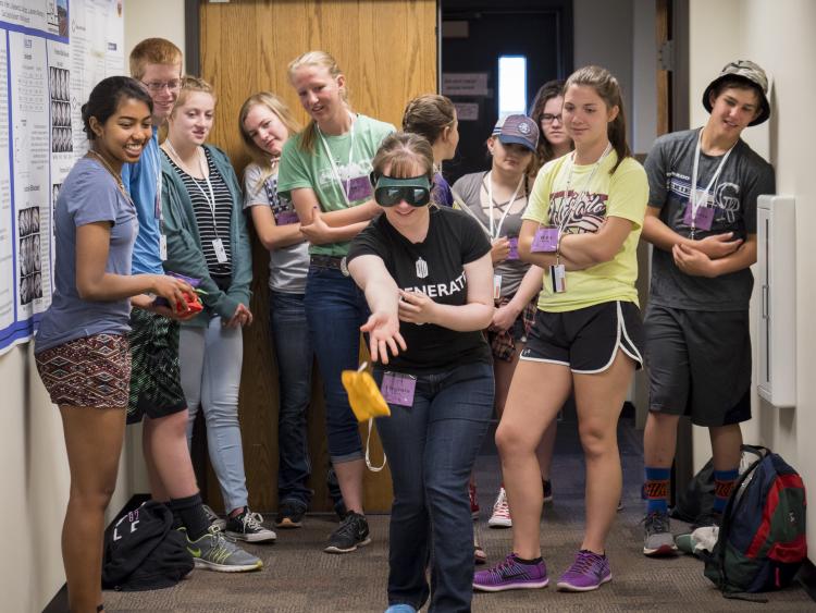 A high school student from Burlington throws a bean bag while wearing vision-distorting goggles