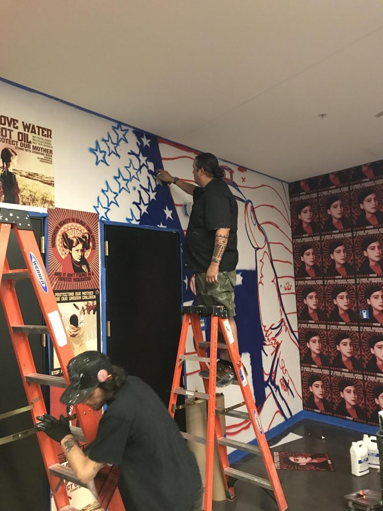 Gregg Deal working on his new campus mural.