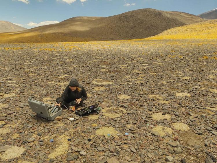 Researcher sits on ground working with computers
