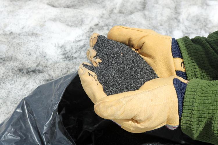 Will Fuller holds a handful of black sand, before tossing it on top of the snow