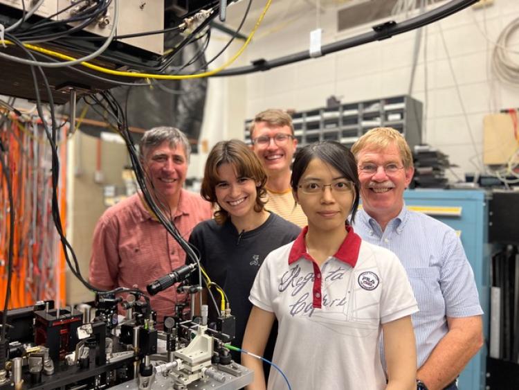 Researchers pose in front of machinery in a lab