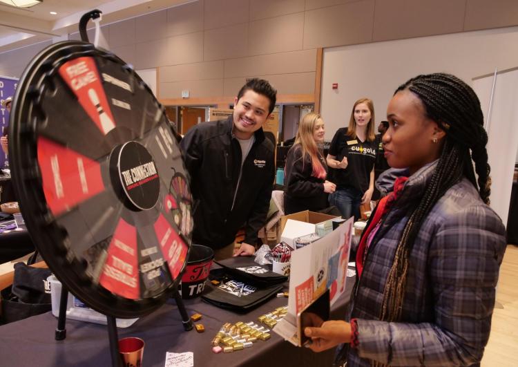 Student spins a prize wheel at The Connection booth at the spring Involvement Fair