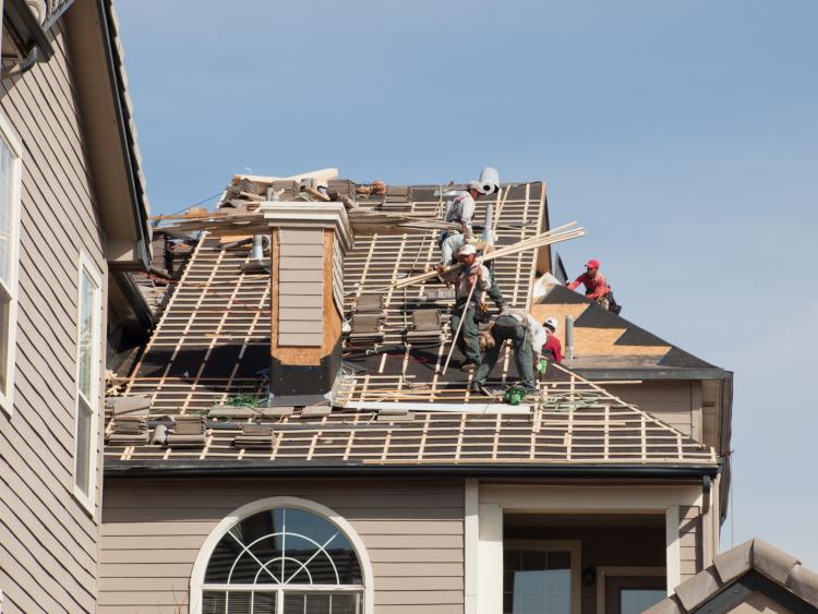 A crew builds the roof of a house.