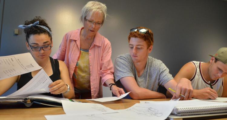 Faculty member Jane Page assists two students in a Shakespeare class