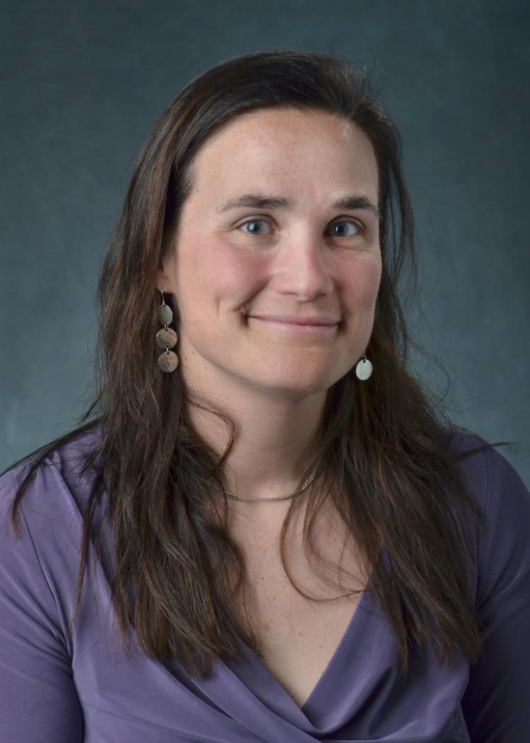A portrait of Jen Kay with a blue background.