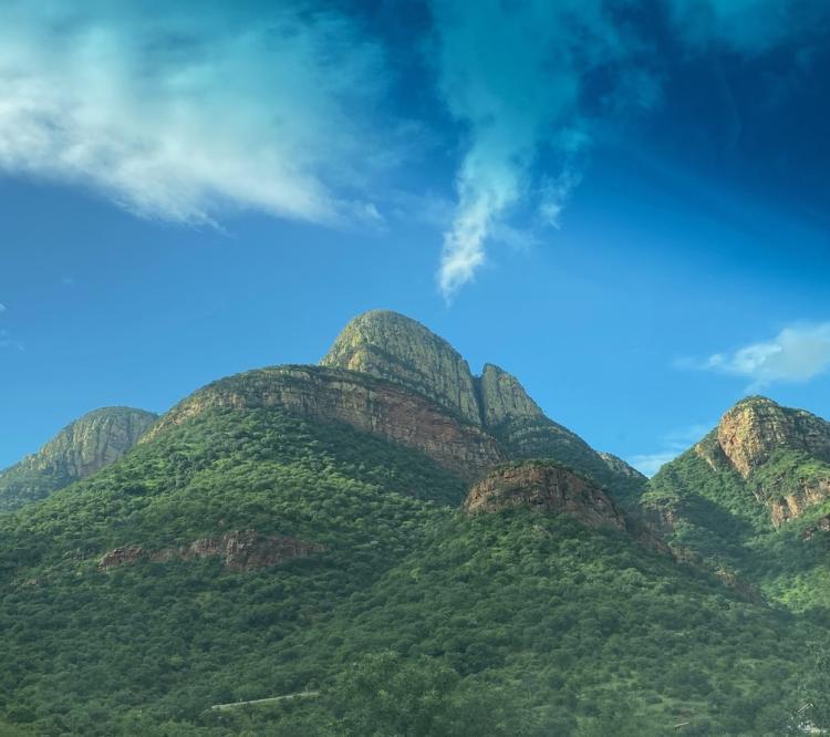 Mountain peaks covered in trees with blue sky and clouds above
